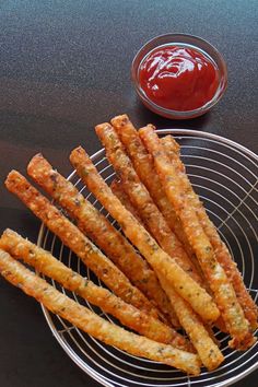 some cheesy bread sticks are on a wire rack next to ketchup