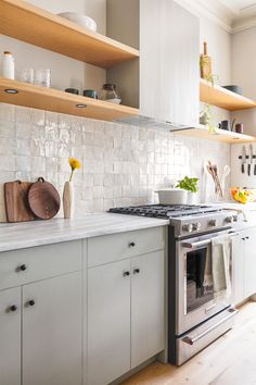 a stove top oven sitting inside of a kitchen next to wooden shelves and counter tops