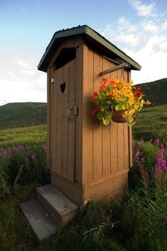 a wooden outhouse with flowers in the window