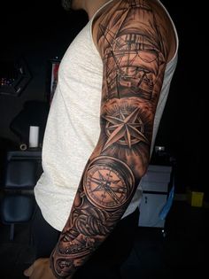 a man's arm with a ship and compass tattoo on the left side of his arm