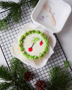 a decorated cake sitting on top of a white tray next to pine cones and evergreen branches