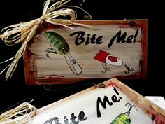 two wooden signs with fishing related artwork on them, one saying bite me and the other saying fly me