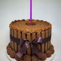 a cake with chocolate frosting and a purple candle on top is sitting on a white plate