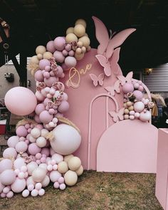 a pink and white balloon arch with balloons attached to it