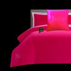 a pink comforter set with two pillows and a pillow case that says juicy on it