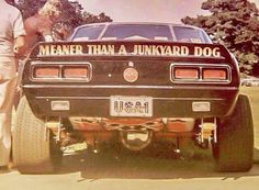 a man standing next to a black car with the words meanier than a junkyard dog on it