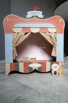 a small wooden stage set with a teddy bear sitting on the floor