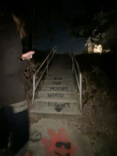 a person walking up some stairs with graffiti on the steps and handrails at night