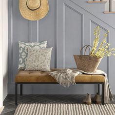 a bench with pillows and a basket on it in front of a stair case that is painted blue