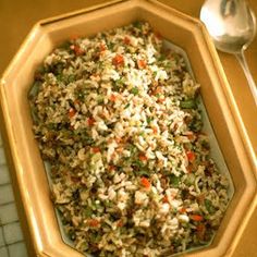 a bowl filled with rice and vegetables on top of a table next to a spoon