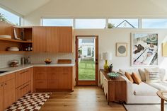 a living room filled with furniture next to a kitchen and an open door leading to a yard