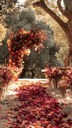 the aisle is lined with rows of chairs covered in rose petals and candles for an outdoor ceremony