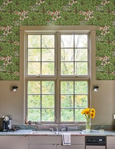 a kitchen with green wallpaper and yellow sunflowers in the window sill