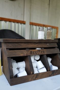 a wooden box filled with coffee cups on top of a table