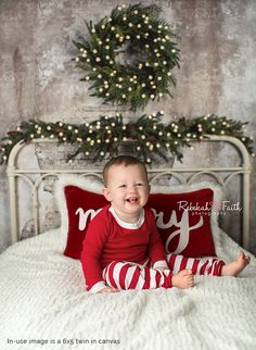 a baby sitting on top of a bed next to a christmas wreath and red pillow