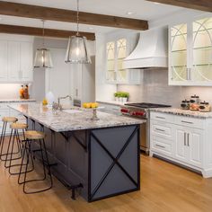 a large kitchen with white cabinets and marble counter tops, along with bar stools