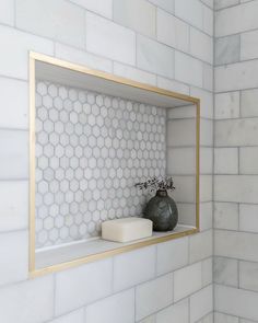 a white tiled bathroom with gold trim and hexagonal tiles on the shower wall