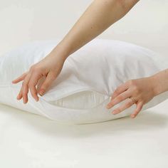 a person reaching for something on top of a white pillow that's turned upside down