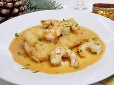 a white plate topped with shrimp and gravy covered in sauce next to pine cones