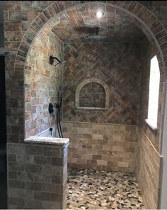 a bathroom with stone walls and flooring in the shower area is seen from an open doorway