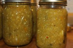 four jars filled with food sitting on top of a wooden table