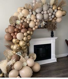 balloons are arranged in the shape of an arch with flowers and leaves on it, near a fireplace