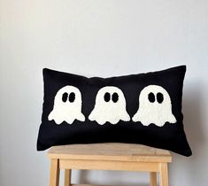 a black pillow with three ghost faces on it