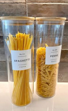 two plastic containers filled with pasta sitting on top of a counter next to each other