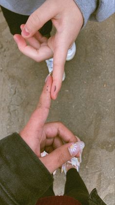 two people standing next to each other with their fingers pointing at the ground and one holding something in his hand