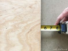 a person measuring the width of a piece of wood with a tape measure in their hand