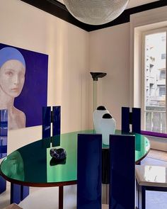 a dining room table with blue chairs and art on the wall