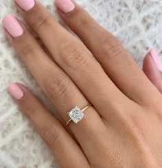 a woman's hand with pink manicured nails and a diamond ring