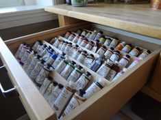 an open drawer filled with lots of condiments on top of a wooden table