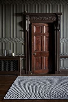 a wooden door sitting in the middle of a room next to a rug and wall