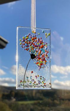 a glass ornament hanging from the side of a window filled with colorful beads