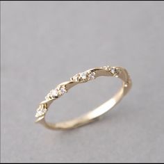 a gold wedding ring with five diamonds on it's side, sitting on a gray surface