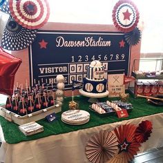 a baseball themed dessert table with red, white and blue decorations on the table top