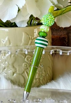 a green and white striped pen sitting on top of a glass vase filled with flowers