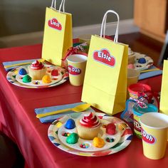 there is a table set up with cupcakes and candy bags on the plates