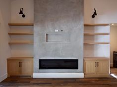 an empty living room with shelves and a fireplace