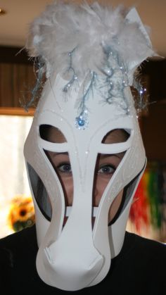 a woman wearing a white mask with feathers on it