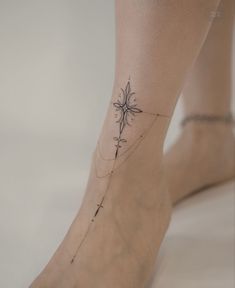 a woman's foot with a cross tattoo on the bottom and ankle, in black ink