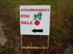 a sign that says strawberries for sale and an arrow pointing to the right with a tomato on it