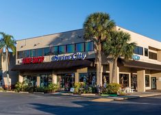 the front of a store with palm trees outside