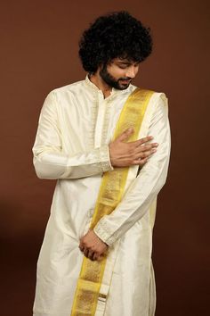 Off-white pattu kurta featuring zardozi and gold thread embroidery on the neckline and sleeve hem. Paired dhoti pant and a kanduva. - Aza Fashions Traditional Pattern Sherwani For Puja, Traditional Sherwani For Puja, Transitional Sherwani With Traditional Patterns For Puja, Traditional Sherwani With Cutdana For Puja, Gold Kurta With Pallu For Puja, Traditional Sherwani With Dabka For Puja, Traditional Gold Kurta For Puja, Off White Traditional Wear With Dabka For Festivals, Traditional Dabka Sherwani For Puja