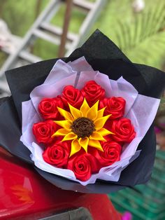 a bouquet of red and yellow roses sitting on top of a car