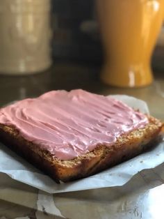 a piece of bread with pink frosting on it sitting on top of a table