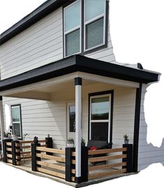 a small white house with black trim on the front porch and covered patio area,