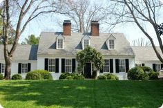 a white house with black shutters and trees