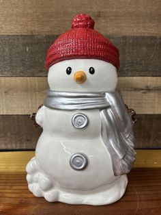 a snowman figurine with a red hat and scarf on it's head